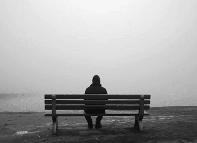 Einsamer Mann auf einer Bank im Nebel